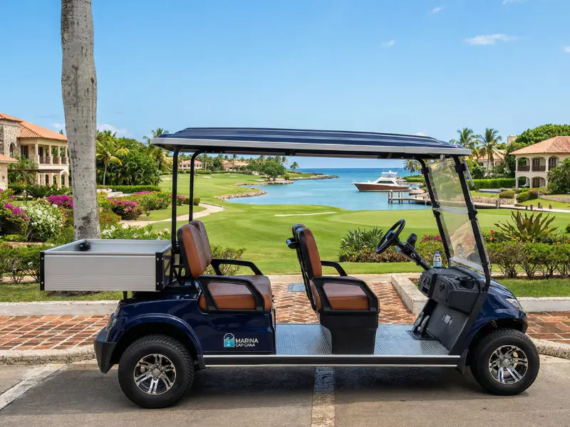 Carrito de golf eléctrico ECO Cross 4 Cargo Box azul marino de cuatro plazas con caja de carga trasera de aluminio frente a una marina
