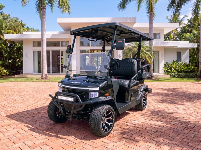 Denago Nomad four-seat electric golf cart in black on a herringbone brick driveway in front of a minimalist white flat-roofed villa with floor-to-ceiling glass doors in Casa de Campo