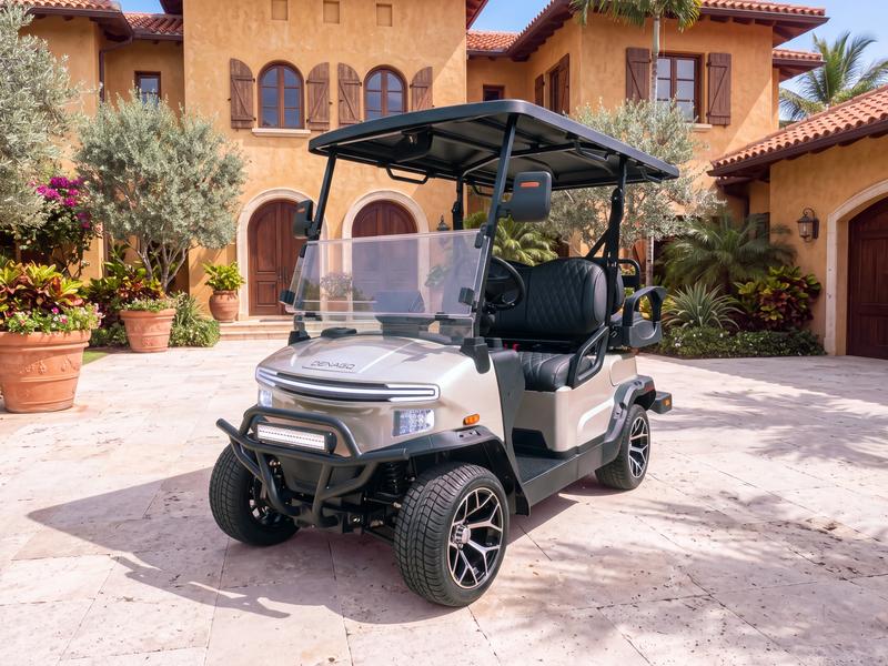 Denago Nomad four-seat electric golf cart in champagne on a pale limestone forecourt in front of a Tuscan-style villa with ochre walls, wooden shutters and terracotta pots in Casa de Campo