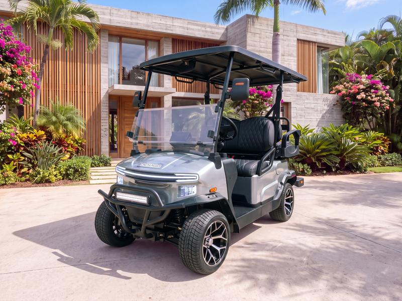 Denago Nomad four-seat electric golf cart in grey on a light concrete driveway in front of a contemporary villa with board-formed concrete walls and teak slats in Casa de Campo
