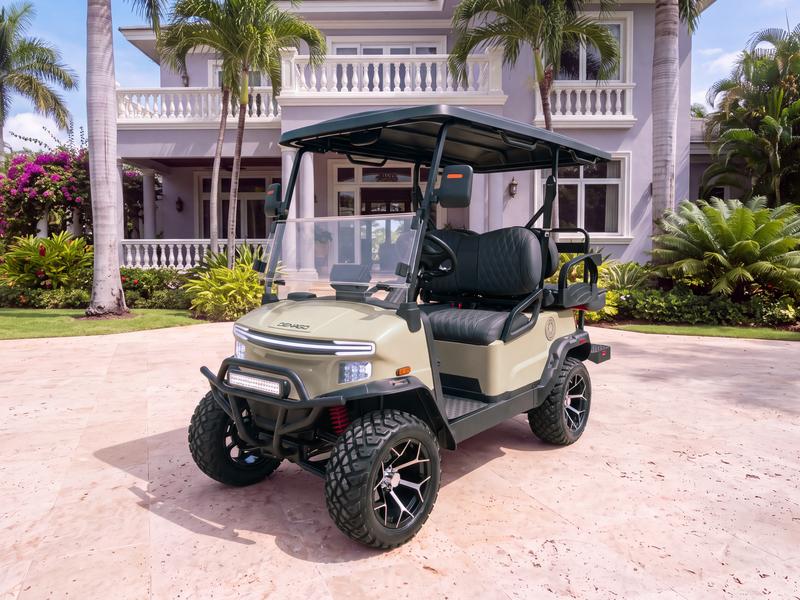 Denago Nomad XL lifted four-seat electric golf cart in khaki on a light stone driveway in front of a lavender-grey villa with white balustrades and coconut palms in Casa de Campo