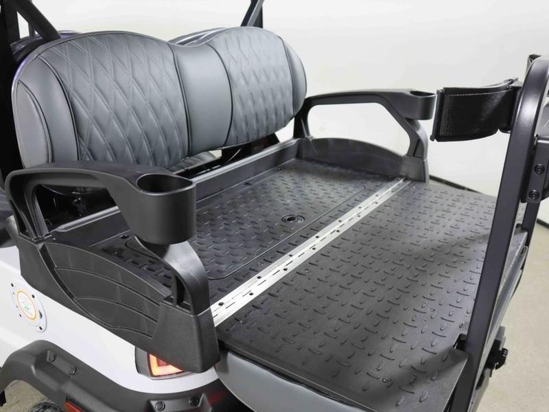Rear flip seat of a Denago golf cart folded down into a flat cargo deck with a non-slip textured surface, between two armrests with cup holders