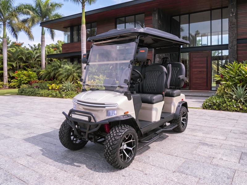 Denago Rover XL four-seat electric golf cart in champagne on a grey granite driveway in front of a modern villa clad in dark wood in Casa de Campo