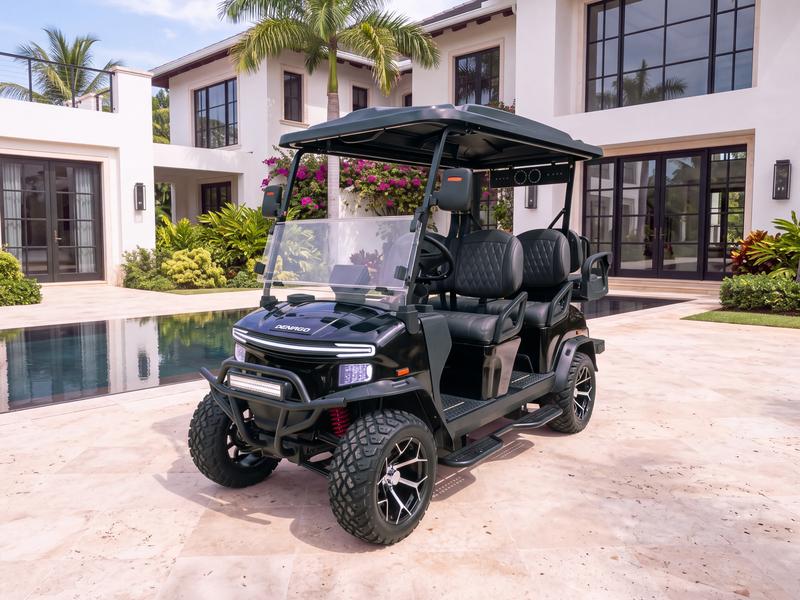 Denago Rover XL6 six-seat electric golf cart in black on a travertine terrace beside a reflecting pool in front of a modern white villa with black steel-framed windows in Casa de Campo