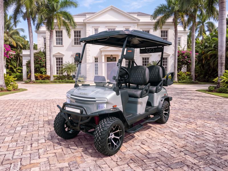 Denago Rover XL6 six-seat electric golf cart in grey on a stone driveway in front of a white Georgian-style villa with a palm-lined drive in Casa de Campo