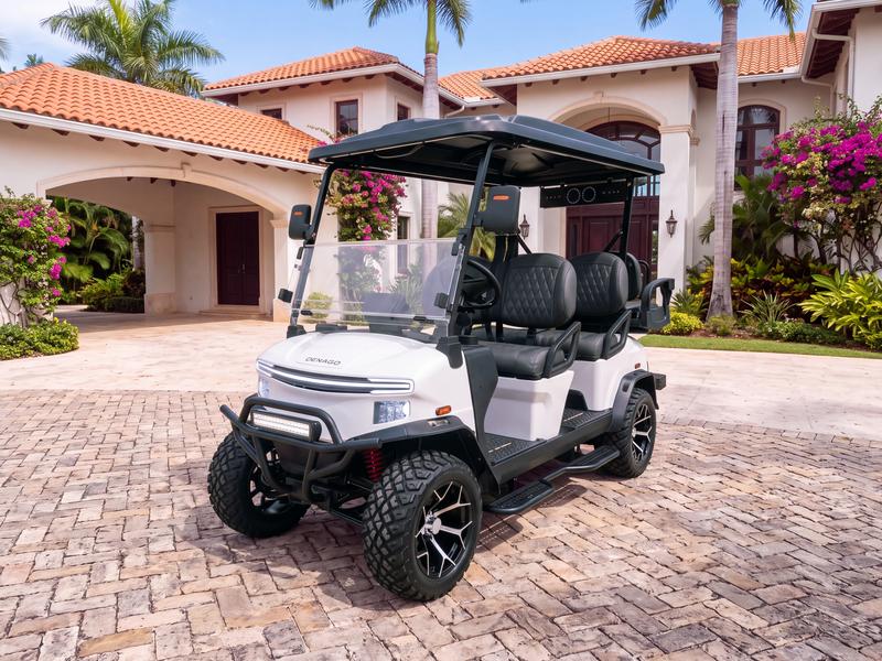 Denago Rover XL6 six-seat electric golf cart in white on a stone driveway in front of a Mediterranean estate villa with an arched porte-cochère in Casa de Campo