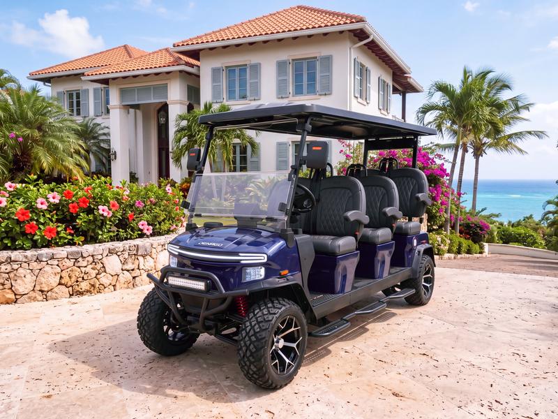 Denago Rover XXL six-seat electric golf cart in navy blue in front of a hillside villa overlooking the Caribbean Sea in Casa de Campo