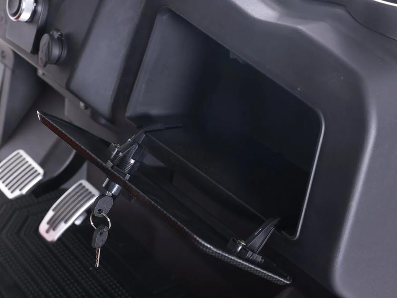 Open lockable glove box in the dashboard of a Denago golf cart, with the key in the lock