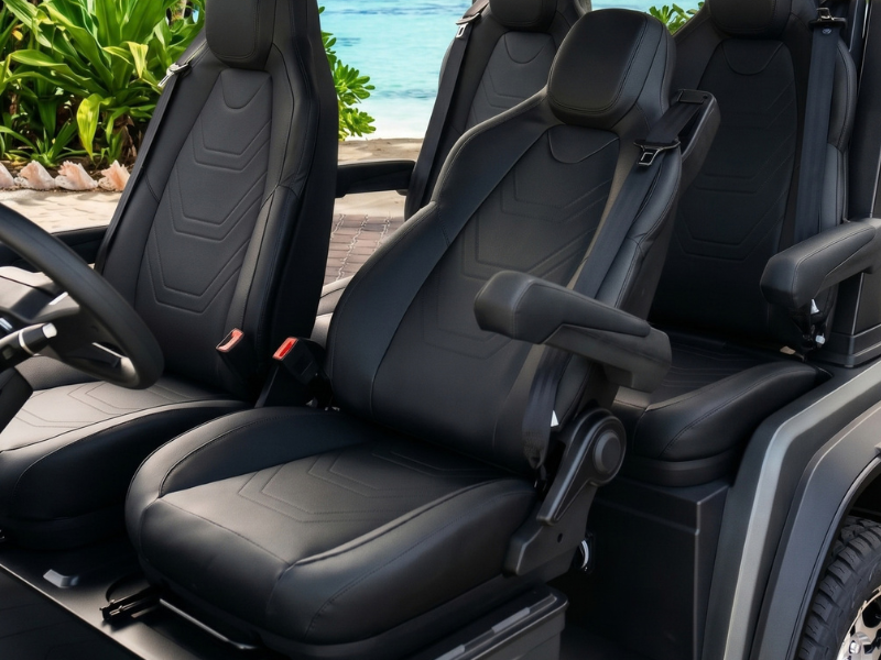 Black front seats of the ECO Azure 4 with armrests, seat belts and the seat adjustment lever